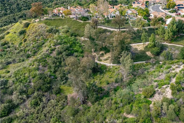 an aerial view of residential house with outdoor space and trees all around