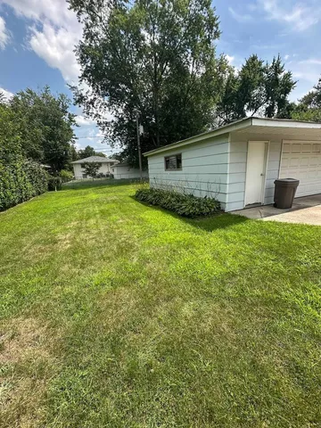 a backyard of a house with plants and large tree