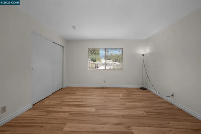 a view of an empty room with wooden floor and a window