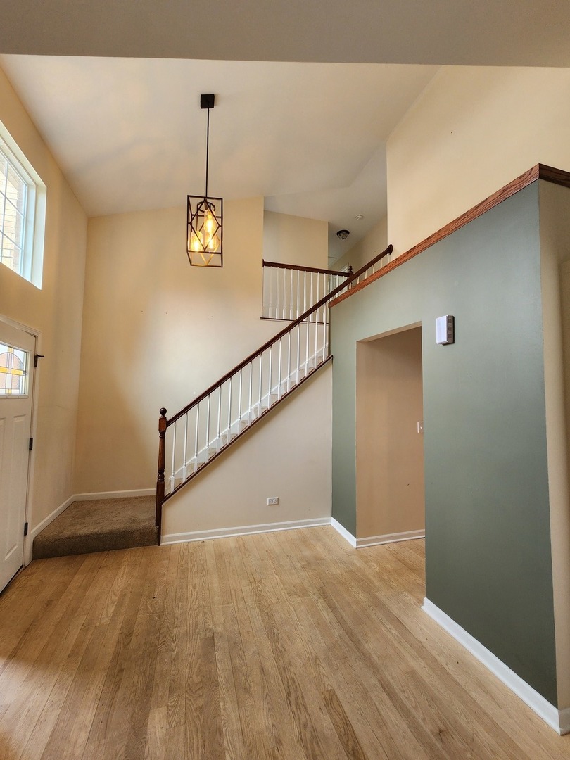 7309 Atkinson Circle Plainfield, IL 60586 - Photo 8 of 38 a view of a hallway with wooden floor and stairs