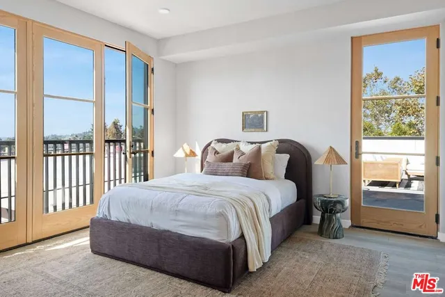 a bedroom with a balcony a bed and a large window