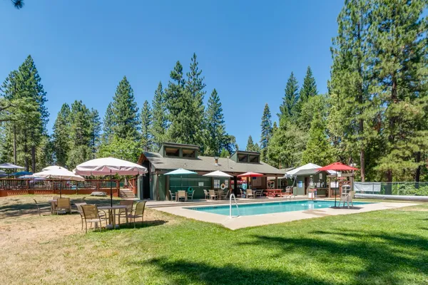a view of a patio with dining table and chairs under an umbrella with a fire pit