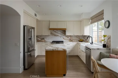 a kitchen with stainless steel appliances granite countertop a refrigerator a stove and a sink