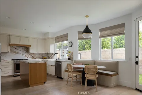 a living room with stainless steel appliances a dining table wooden floor and a large window