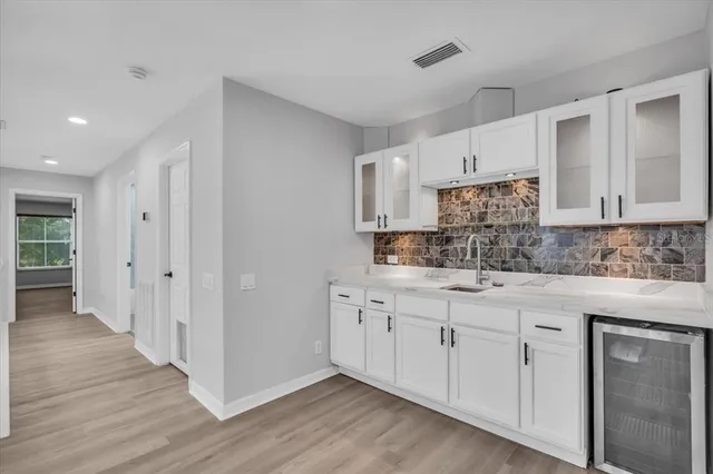 a kitchen with white cabinets and sink