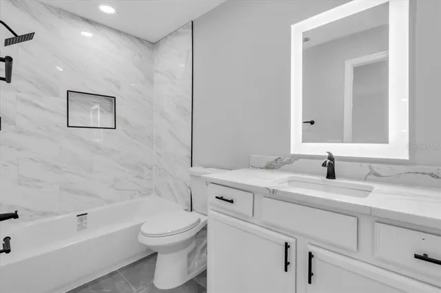 a bathroom with a granite countertop sink a toilet and bathtub