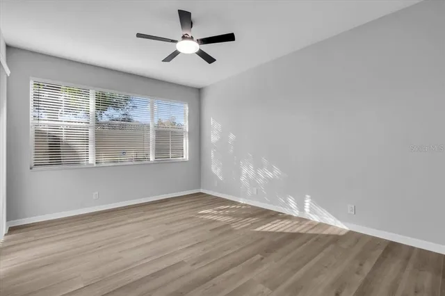 a view of an empty room with wooden floor and a window
