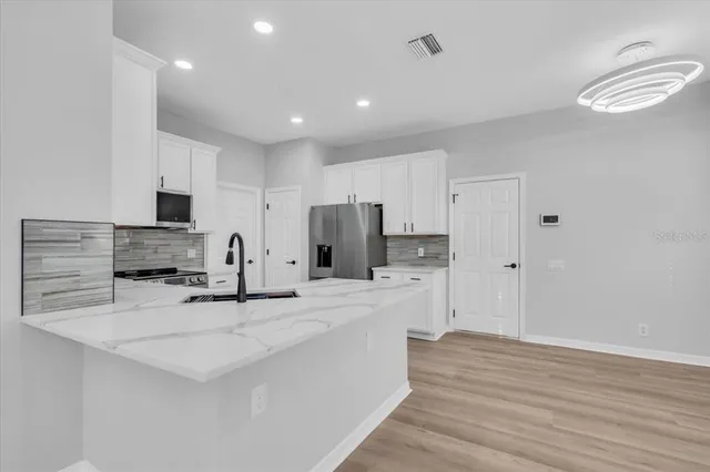 a large kitchen with kitchen island a sink stainless steel appliances and cabinets