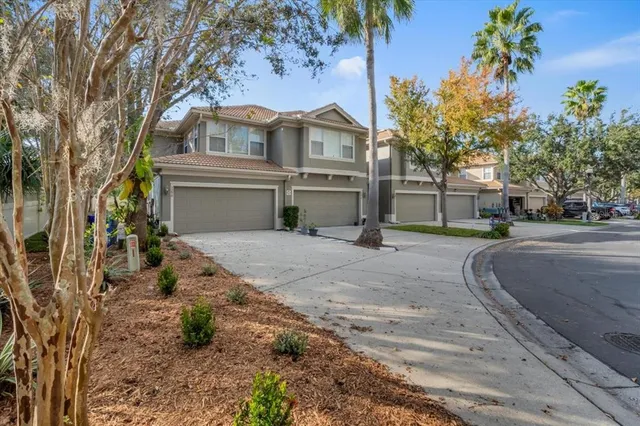 a view of a white house next to a yard with big trees
