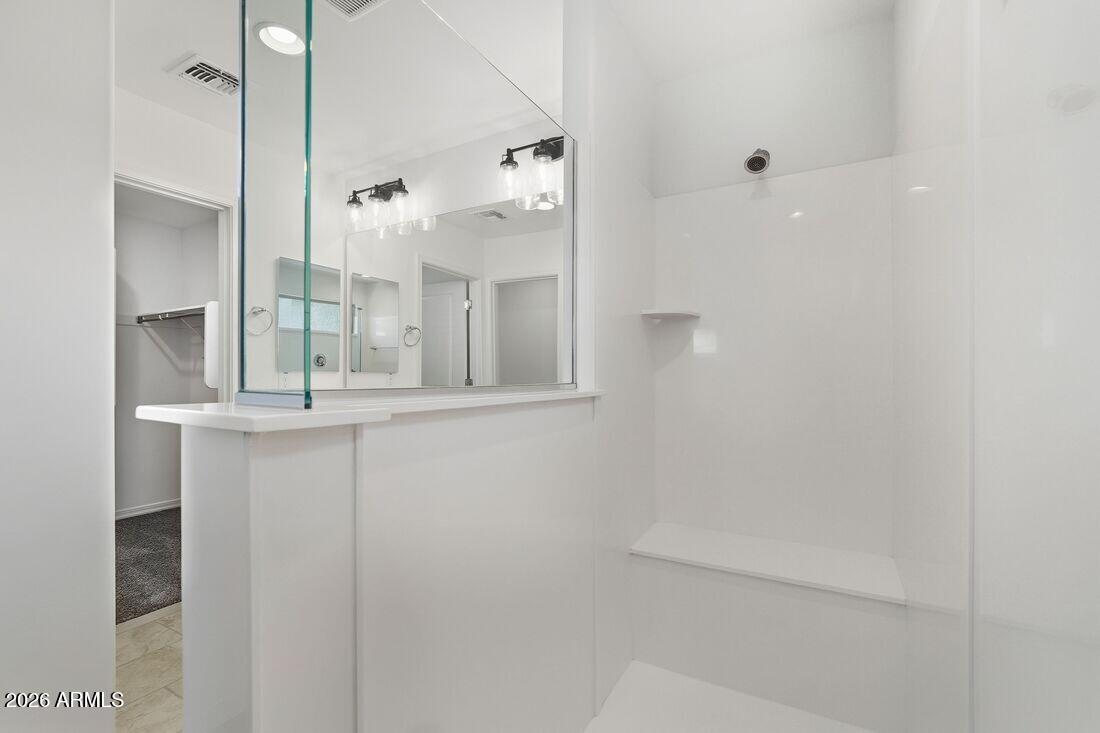 10048 West Piccadilly Road Avondale, AZ 85392 - Photo 21 of 49 a bathroom with a glass shower door and a mirror
