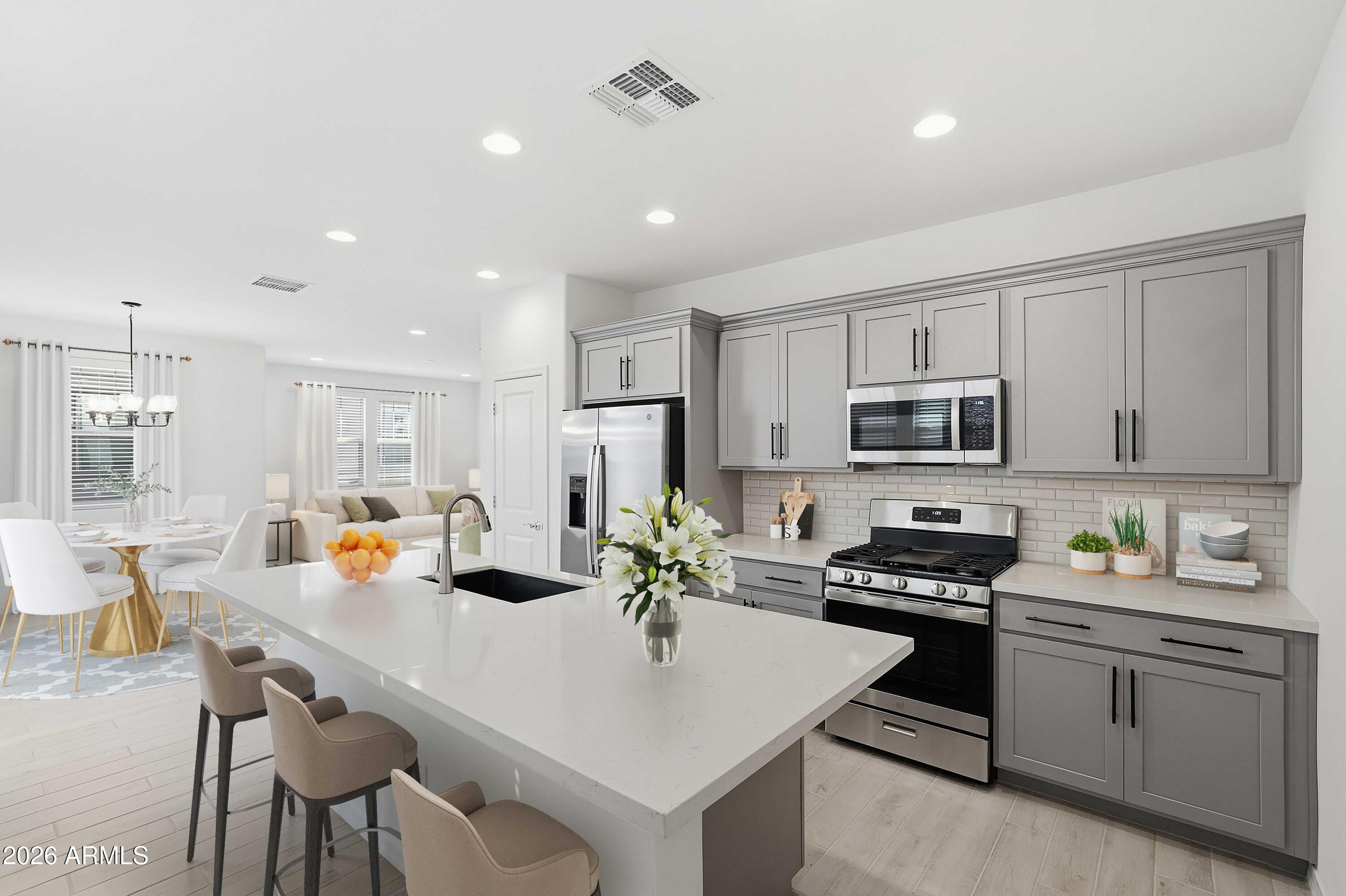 10048 West Piccadilly Road Avondale, AZ 85392 - Photo 3 of 49 a kitchen with stainless steel appliances granite countertop a stove refrigerator a sink dishwasher a dining table and chairs with wooden floor