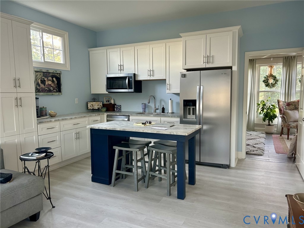 a kitchen with stainless steel appliances a sink a stove a refrigerator cabinets and a dining table