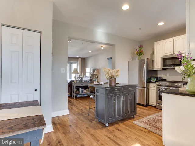 a kitchen with stainless steel appliances granite countertop a stove top oven a sink dishwasher and a refrigerator with wooden floor