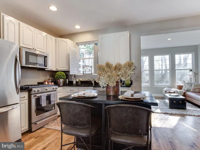 a kitchen with stainless steel appliances granite countertop a stove top oven a sink dishwasher a dining table and chairs with wooden floor