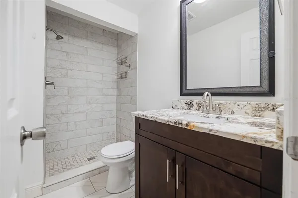 a bathroom with a granite countertop sink toilet a mirror and shower