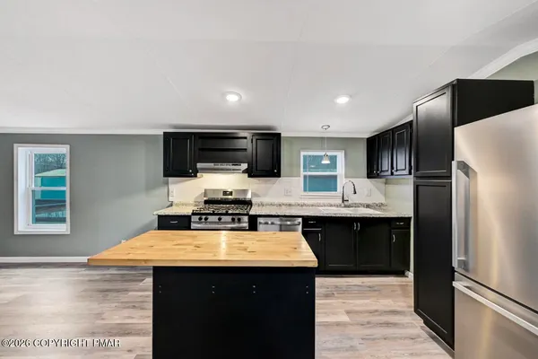 a kitchen with stainless steel appliances granite countertop a refrigerator a stove a sink dishwasher and a microwave oven with wooden floor
