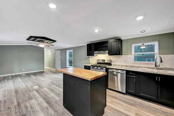 a kitchen with stainless steel appliances a stove a refrigerator a sink a stove white cabinets and wooden floor