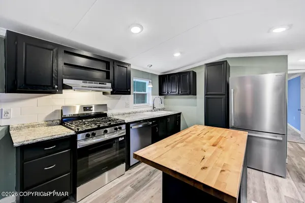 a kitchen with stainless steel appliances granite countertop a refrigerator and a stove top oven