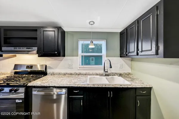a kitchen with stainless steel appliances kitchen island granite countertop a stove refrigerator and microwave