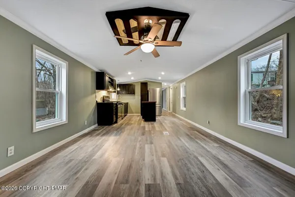 a view of a livingroom with a flat screen tv wooden floor and a ceiling fan