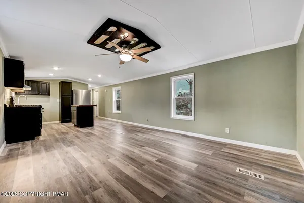 a view of a room with wooden floor ceiling fan and windows