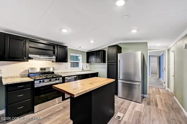 a kitchen with stainless steel appliances granite countertop a stove top oven a sink dishwasher with wooden cabinets and floor