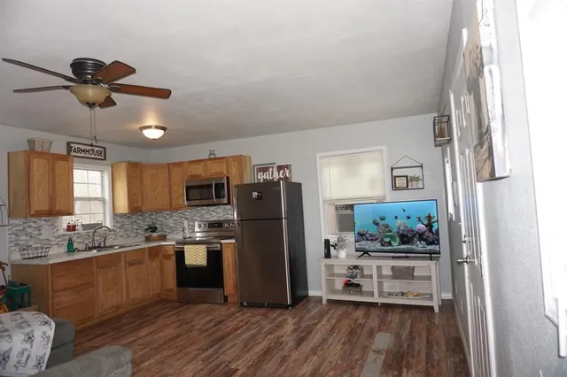 a kitchen with stainless steel appliances granite countertop a refrigerator a stove a sink and white cabinets with wooden floor