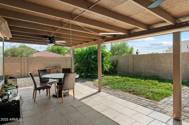 a view of patio with a table and chairs under an umbrella with a small yard
