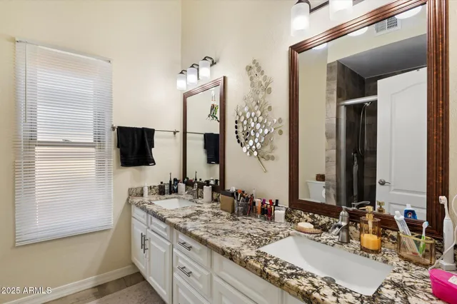 a bathroom with double vanity and a mirror