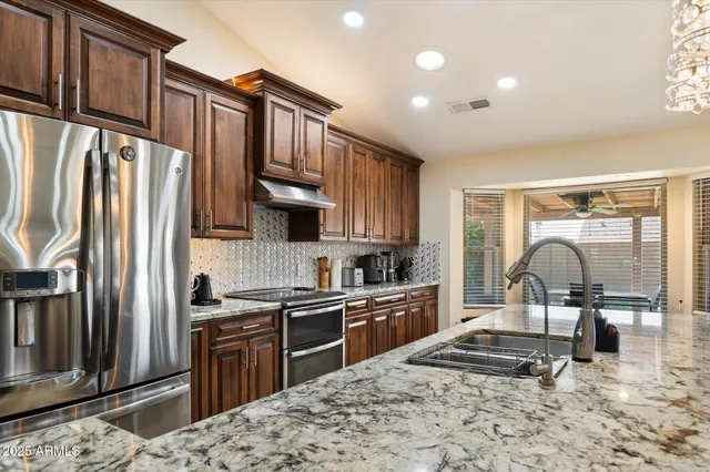 a kitchen with stainless steel appliances granite countertop a sink stove refrigerator and cabinets