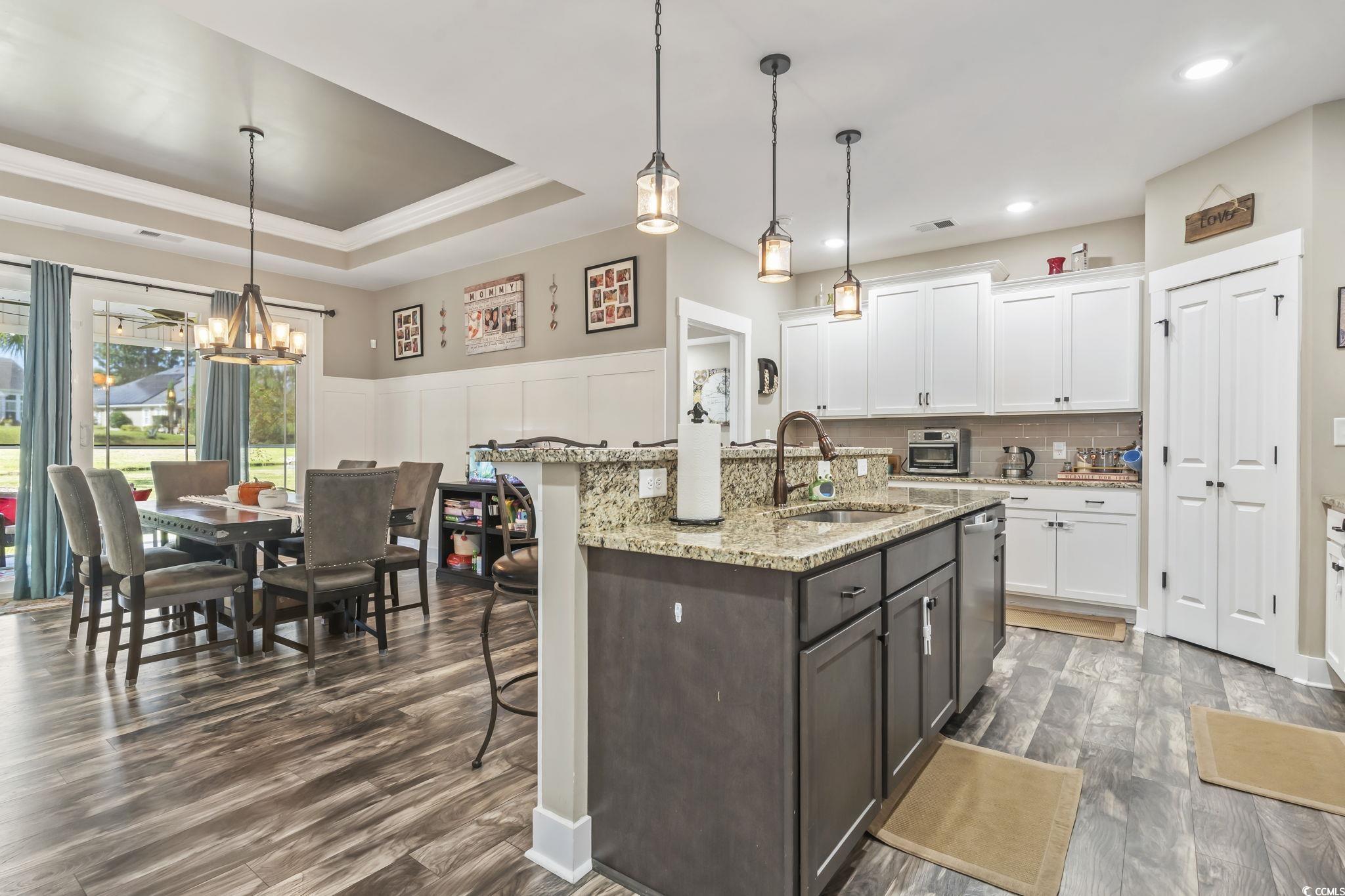 175 Rivers Edge Drive Conway, SC 29526 - Photo 11 of 37 Kitchen featuring white cabinetry, hanging light fixtures, light stone counters, a kitchen island with sink, and dark wood-style flooring