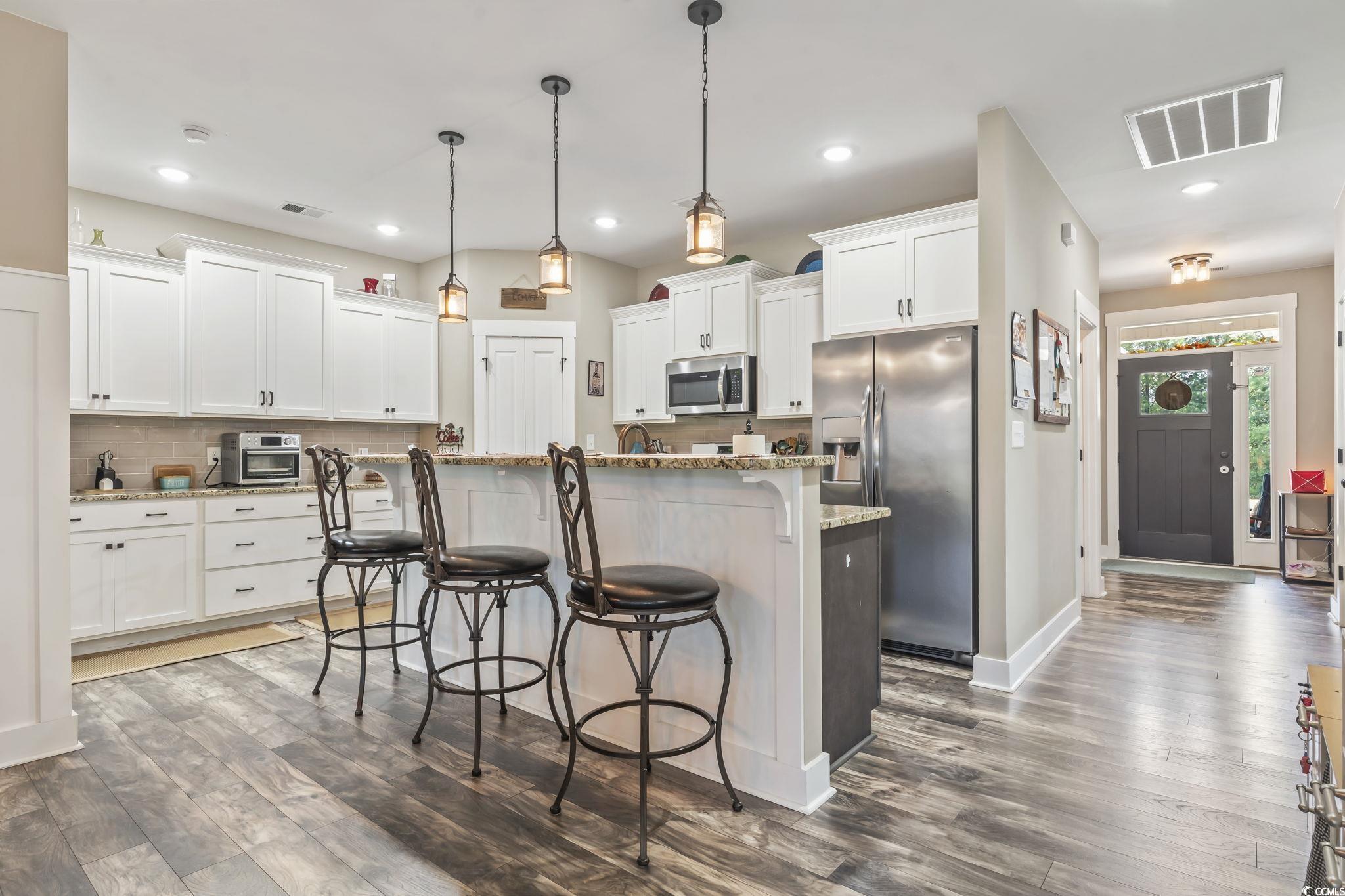 175 Rivers Edge Drive Conway, SC 29526 - Photo 12 of 37 Kitchen with a breakfast bar area, backsplash, stainless steel appliances, pendant lighting, and white cabinets