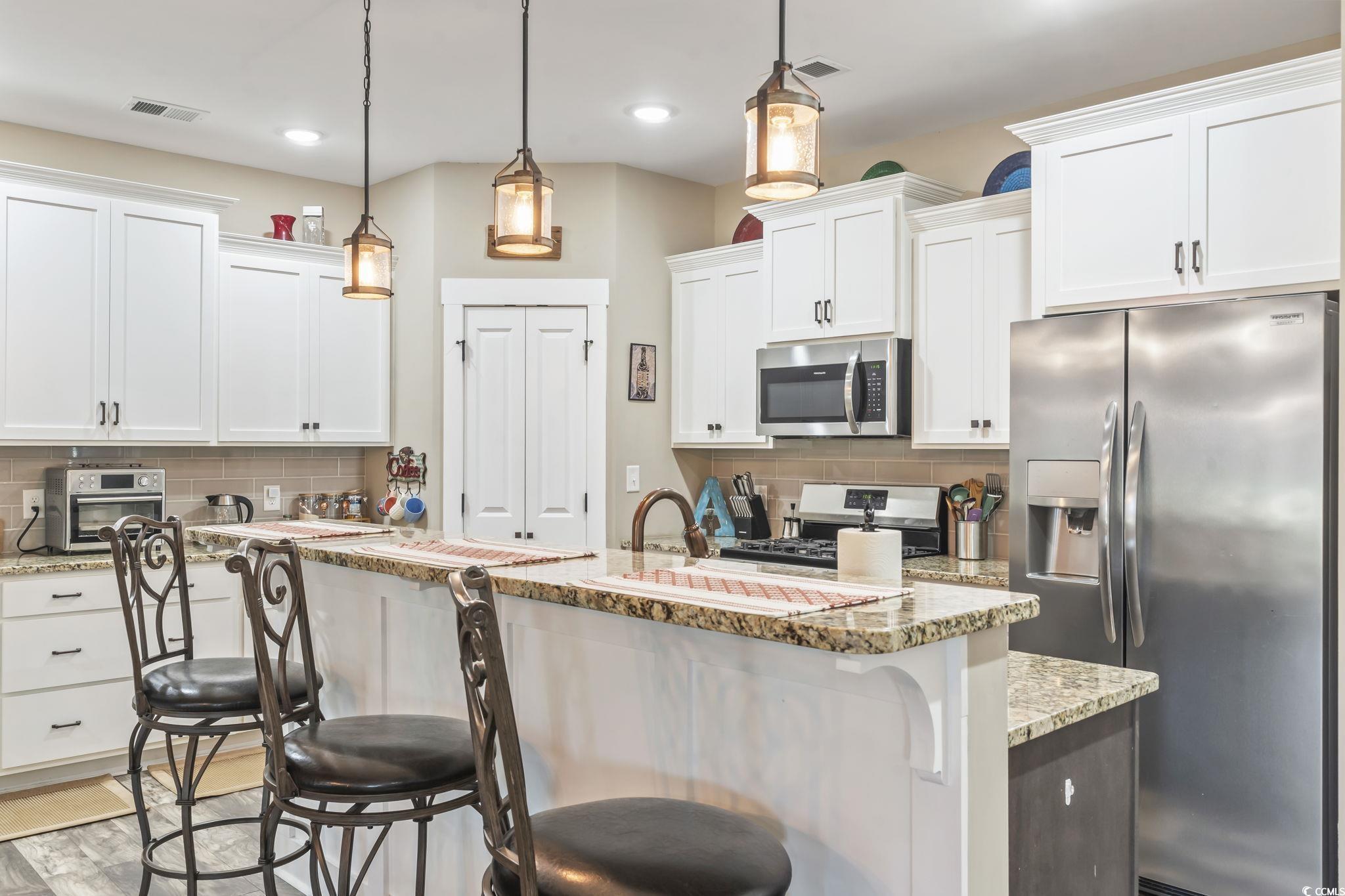 175 Rivers Edge Drive Conway, SC 29526 - Photo 7 of 37 Kitchen featuring stainless steel appliances, a breakfast bar area, decorative backsplash, and light stone counters
