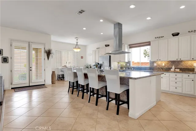 a kitchen with stainless steel appliances granite countertop a stove a sink a microwave a refrigerator and chairs