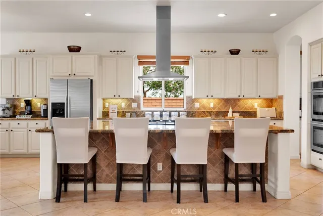 a kitchen with stainless steel appliances kitchen island granite countertop a sink stove refrigerator and cabinets