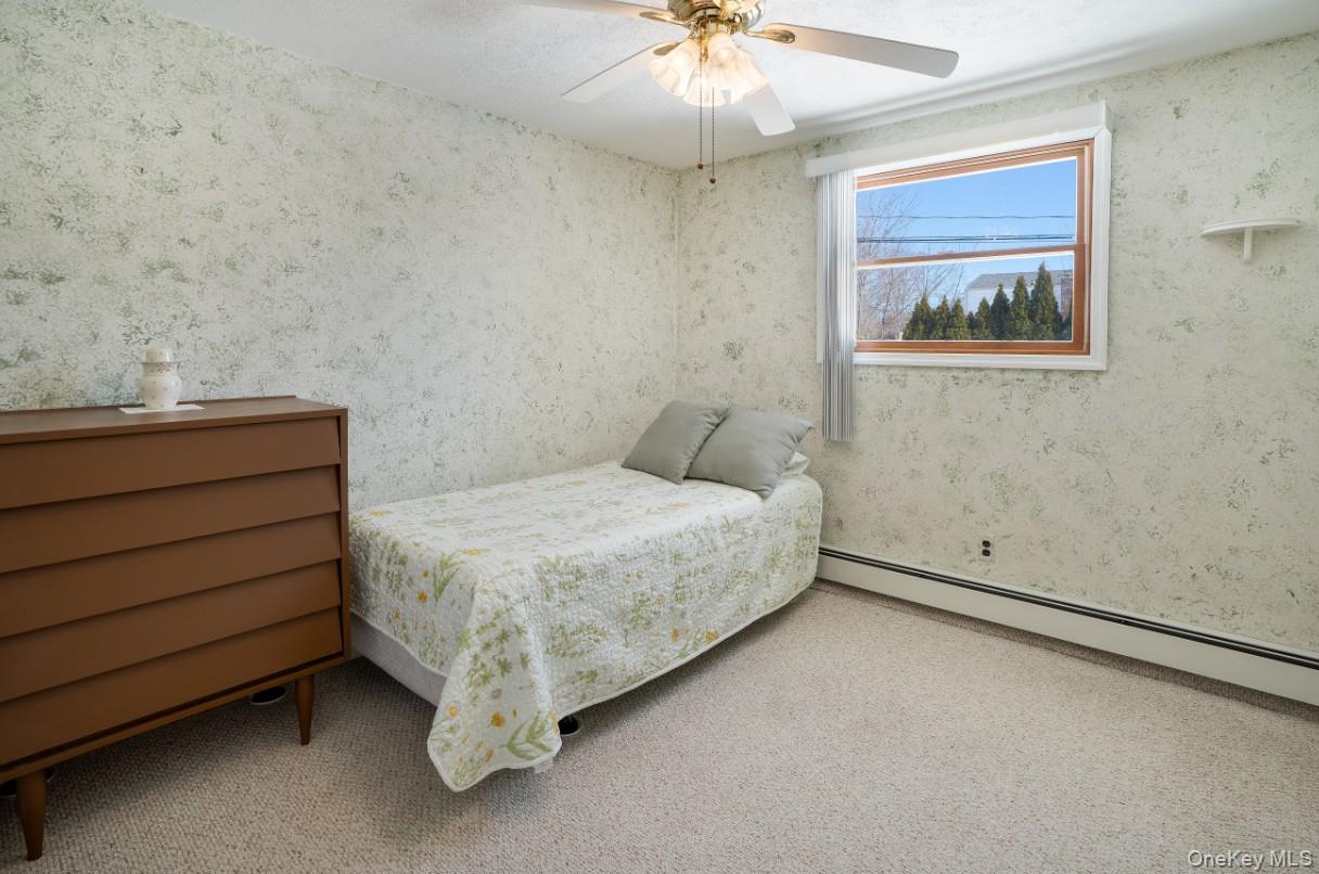 69 Riviera Drive Selden, NY 11784 - Photo 18 of 20 a spacious bedroom with a bed and a chandelier