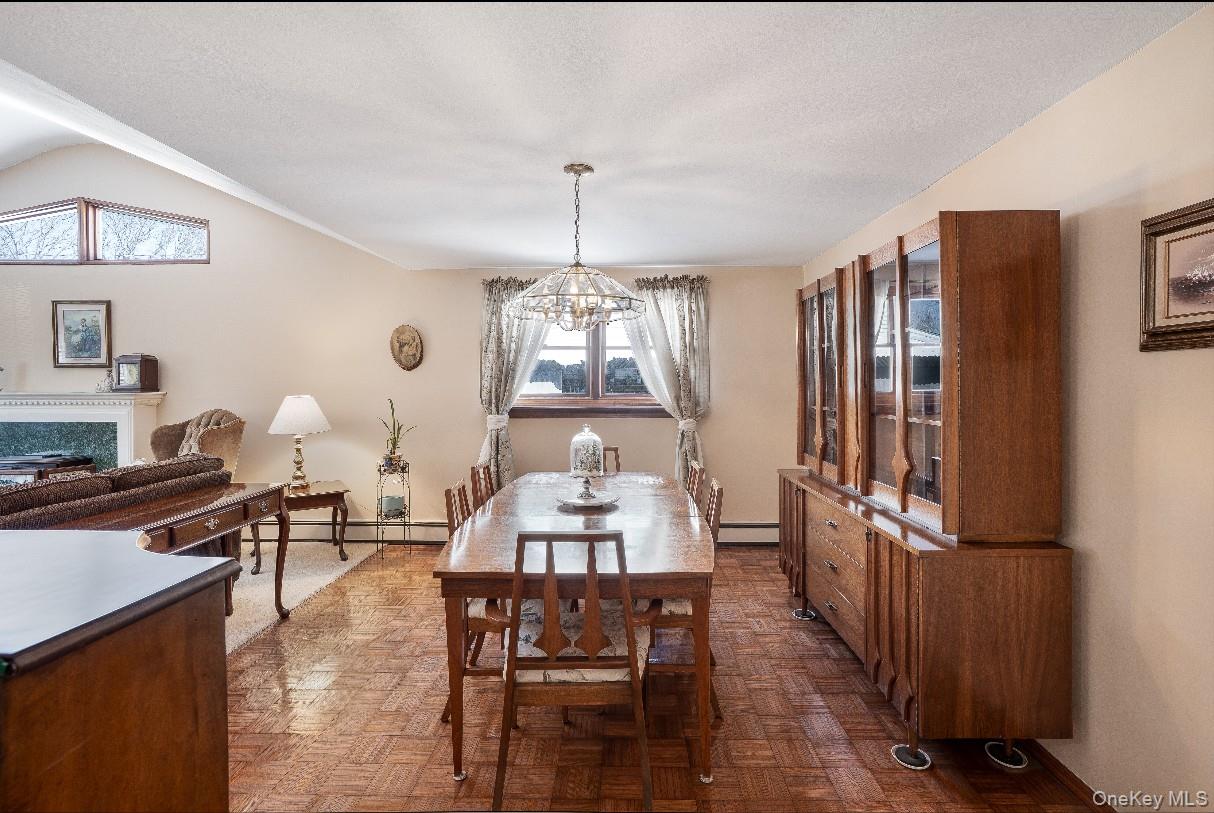 69 Riviera Drive Selden, NY 11784 - Photo 8 of 20 a dining room with wooden floor a chandelier a wooden table and chairs