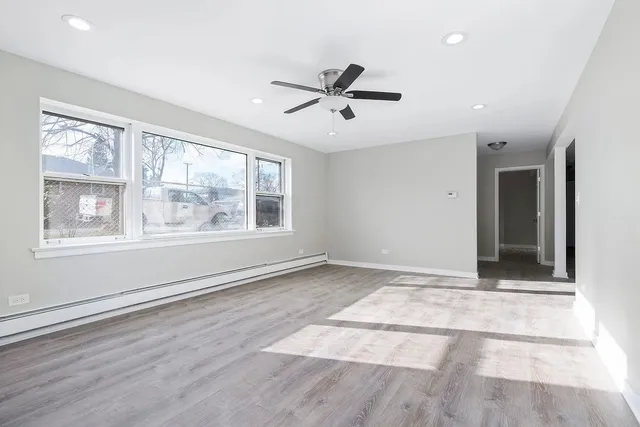a view of an empty room with a window and wooden floor