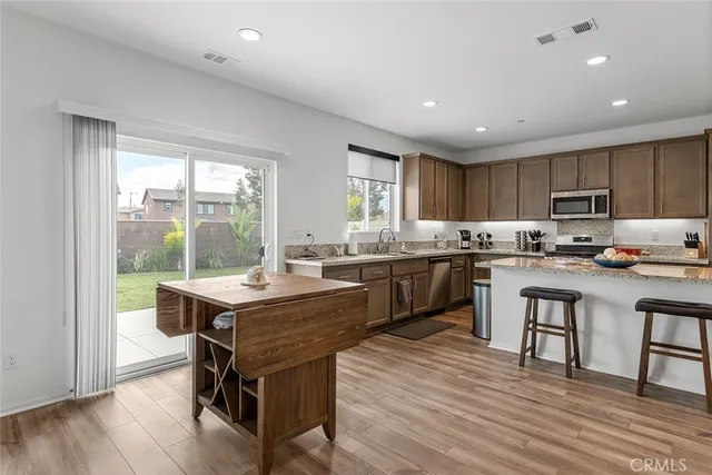 a kitchen with a table chairs a sink dishwasher a refrigerator and cabinets with wooden floor