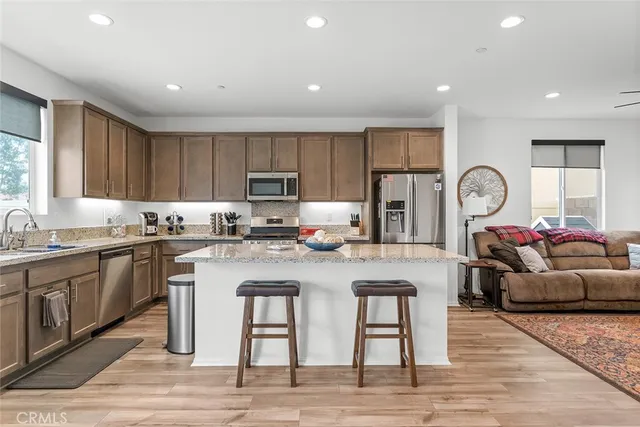 a kitchen with stainless steel appliances granite countertop a table chairs sink refrigerator and cabinets