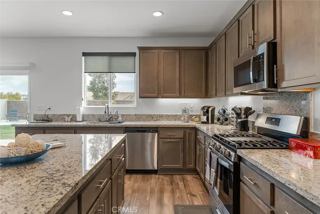 a kitchen with stainless steel appliances granite countertop a stove a sink and a microwave