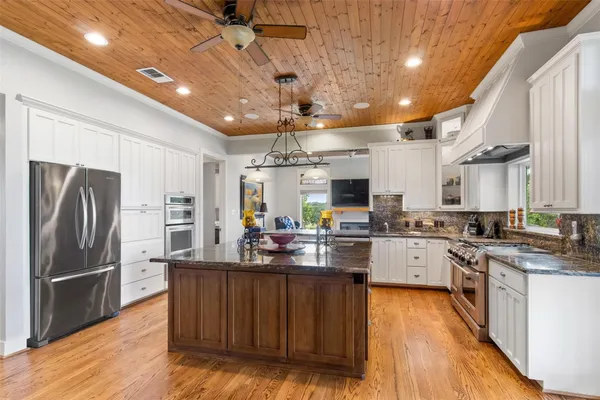a large white kitchen with granite countertop a stove a sink and dishwasher a granite countertops with wooden floor