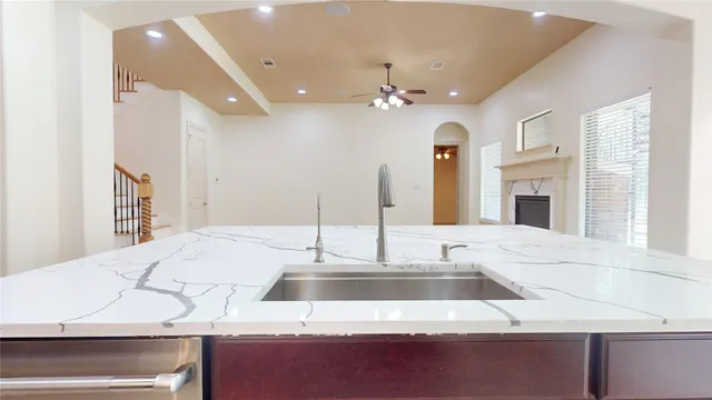 a kitchen with kitchen island granite countertop a sink and a refrigerator