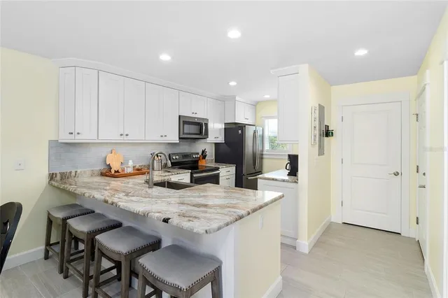 a kitchen with granite countertop a refrigerator stove and sink