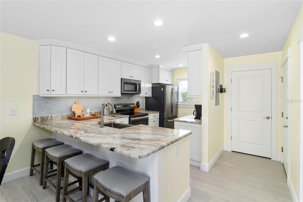 460-5 Gulf Boulevard, Unit 4 Boca Grande, FL 33921 - Photo 4 of 26 a kitchen with kitchen island granite countertop a sink cabinets and refrigerator