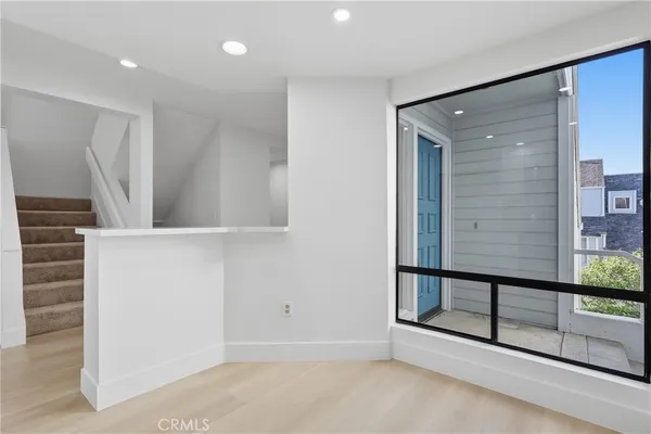 an empty room with wooden floor fireplace and windows