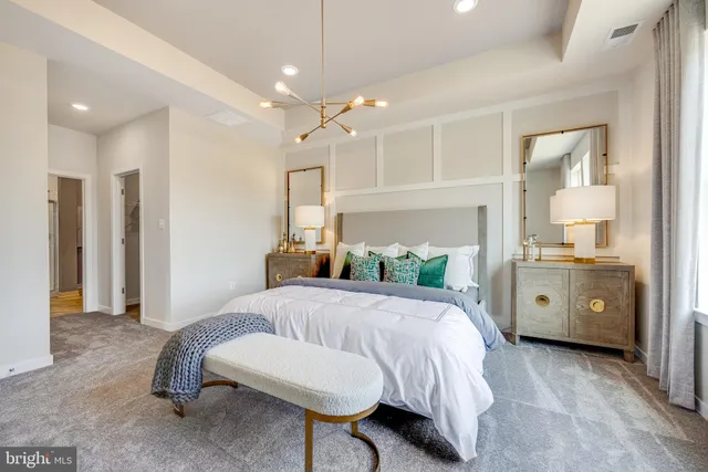 a spacious bedroom with a bed a chandelier and a mirror