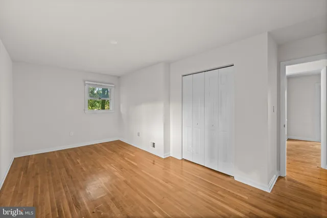 an empty room with wooden floor and window