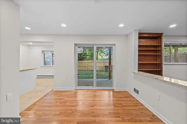 a view of an empty room with a window and wooden floor