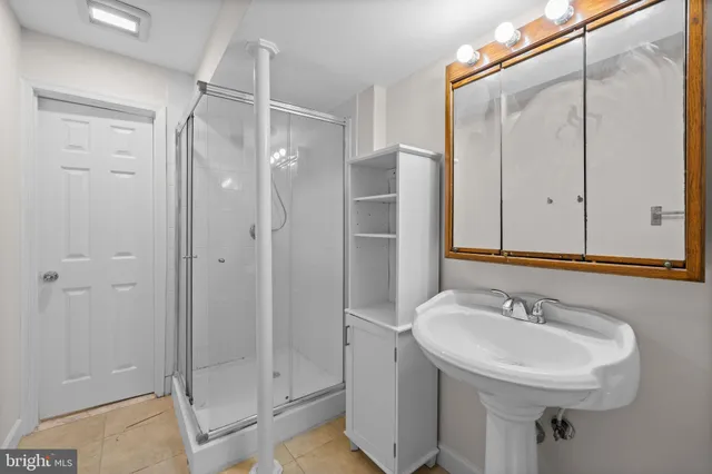 a bathroom with a sink shower and a mirror